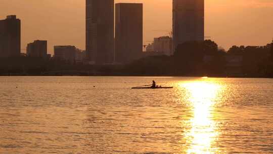 夕阳下一位运动员在湖面上划船