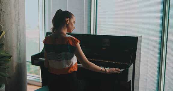 靠近窗户弹钢琴的女人