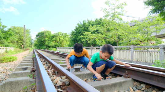 两个小孩坐在铁路上玩耍