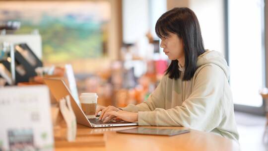 年轻女子在咖啡馆使用笔记本电脑上网