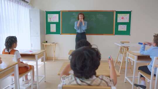 高加索年轻女子教师在学校教室教学生。