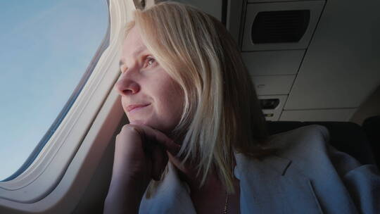 女人望向飞机窗外视频素材模板下载