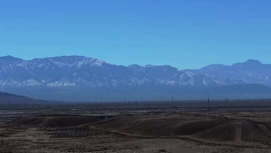 大气航拍西北戈壁滩上的公路及远方的雪山