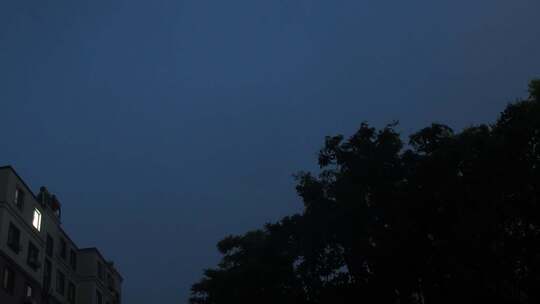 雨夜窗外的城市居民楼灯光和闪电