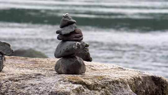 在海边一块巨石上堆叠的两个小石柱的缓慢跟踪镜头。