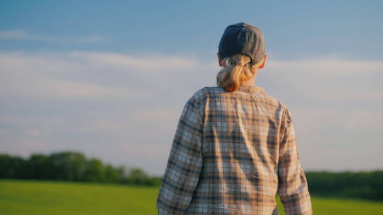 一名女农民在麦田中行走的后视图
