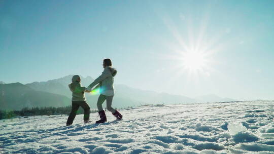 女孩和妈妈在雪地里手拉手转圈圈