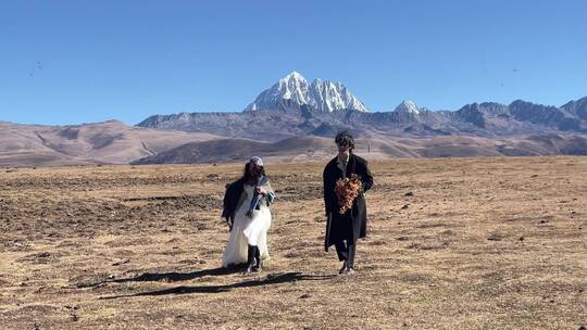 高原枯黄草原雪山情侣奔跑慢动作拍写真婚纱