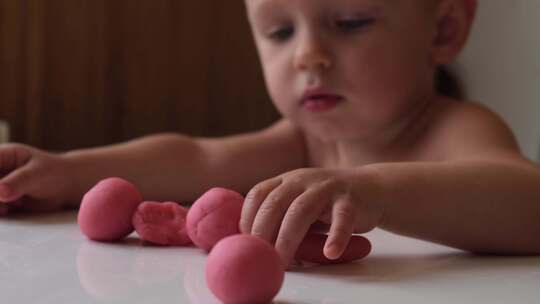 婴儿玩粉红色橡皮泥，早期与儿童一起塑造发