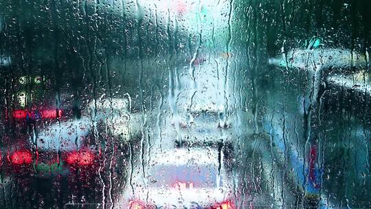 下雨玻璃上滴落的雨滴雨水映射五彩车灯