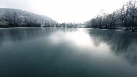 FPV无人机航拍雪景白雪森林中的村镇河流