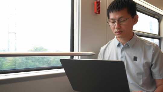 中年男子在火车上使用笔记本电脑工作