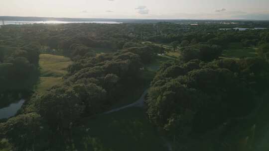 美丽日落时高尔夫球场上绿草和树木的鸟瞰图视频素材模板下载