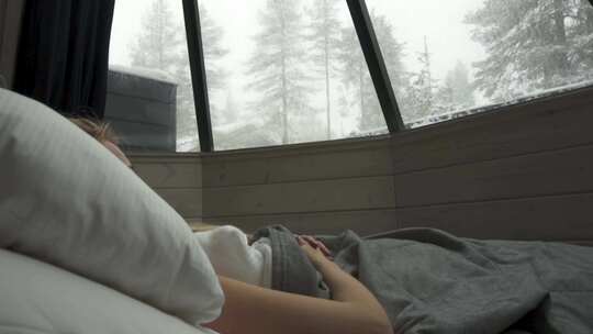美女躺在床上看窗外森林雪景民宿度假酒店视频素材模板下载