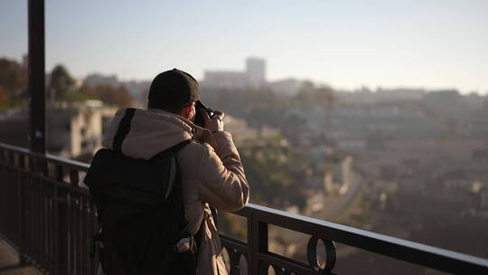 旅行摄影师站在桥上用相机拍照
