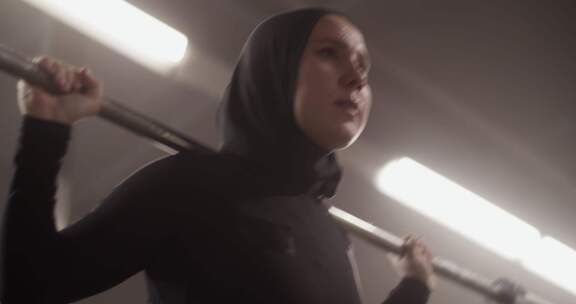 坚定的穆斯林女运动员用杠铃锻炼