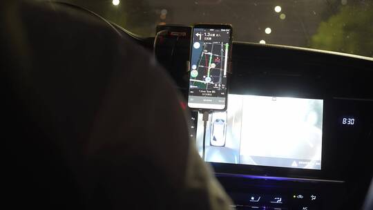 网约车司机按手机导航APP行驶在夜晚城市