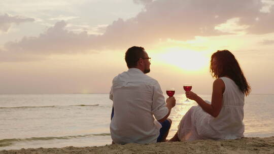 一对年轻夫妇在海边喝酒看着日出视频素材模板下载
