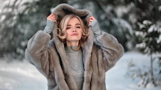 冬季林地穿着天然灰色兜帽毛皮大衣的可爱女性肖像视频素材模板下载