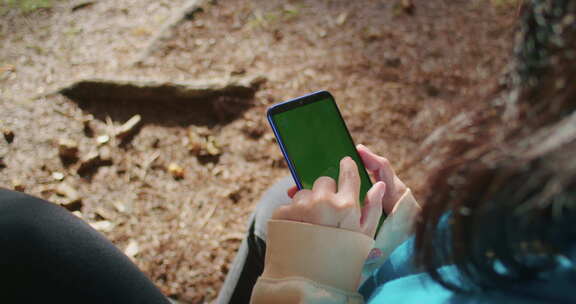 女子使用智能手机的肩上照片，绿屏模糊自然