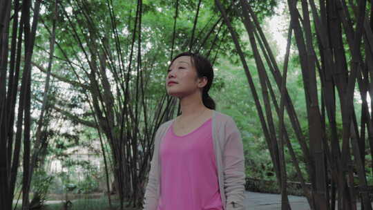 美丽女人在公园竹林中漫步放松心情感受自然