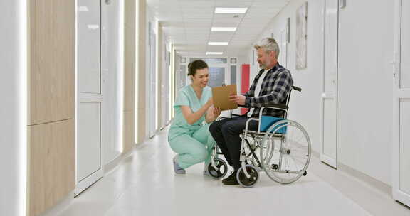 一名坐在轮椅上的中年男子在医院走廊与护士