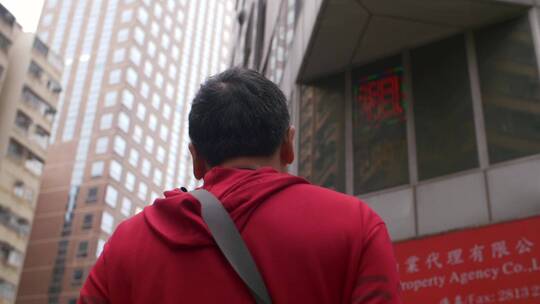 一个穿红衣服的男人走在香港街道上低角度拍摄