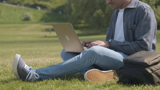 在草坪上使用笔记本电脑工作的男人