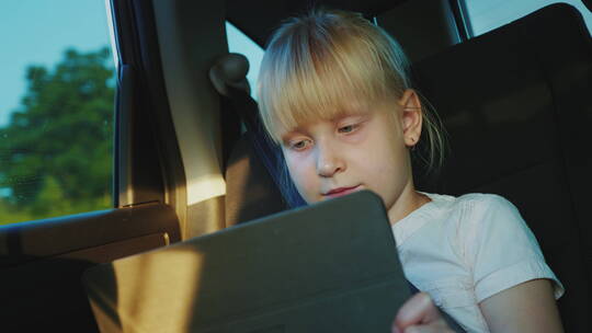 6岁白人女孩在车后座玩平板电脑