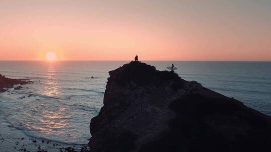 冲浪者在岸边欣赏海洋日落美景