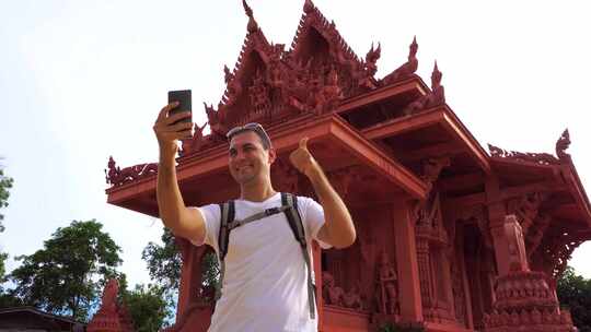 年轻男性旅行者与亚洲佛教寺庙自拍。