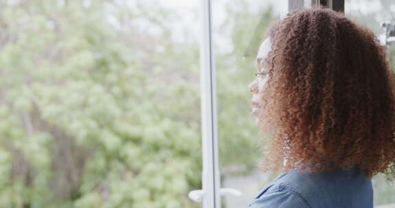年轻的非裔美国妇女在家窗边微笑，有复印空