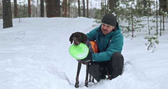 一个快乐的男人在多雪的冬季森林里遛狗