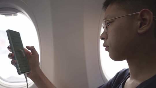 男孩在飞机上使用手机视频素材模板下载