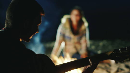 夜晚男人在篝火旁给女朋友弹吉视频素材模板下载