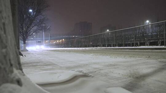 城市夜晚大雪街道路边行驶车流