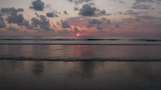 日落时海岸线和海浪的无人机视图