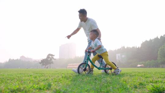 公园草地上父亲教孩子骑车视频素材模板下载