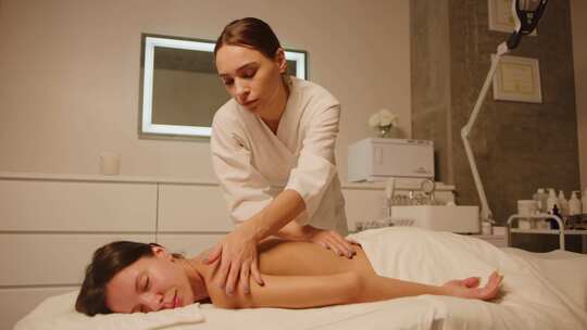 女人躺在按摩台上，一边按摩一边微笑