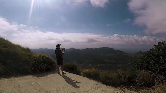 用手机拍摄山景的男人