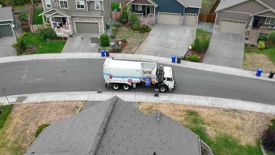 一架垃圾车从美国社区的路边装载垃圾箱的无人机视图。