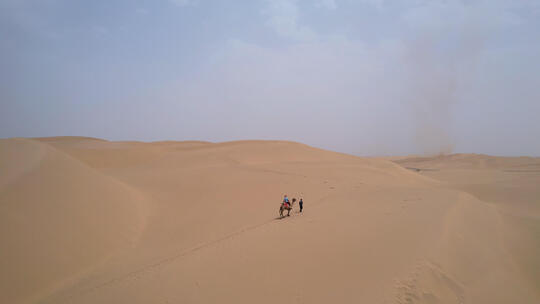 航拍新疆塔克拉玛干沙漠上骑骆驼的游客