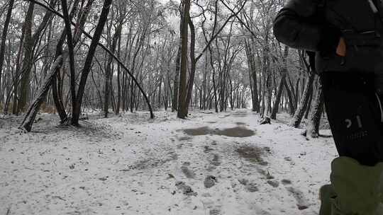 一个男人走在白雪皑皑的森林里