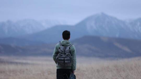 男子背背包眺望远方山脉