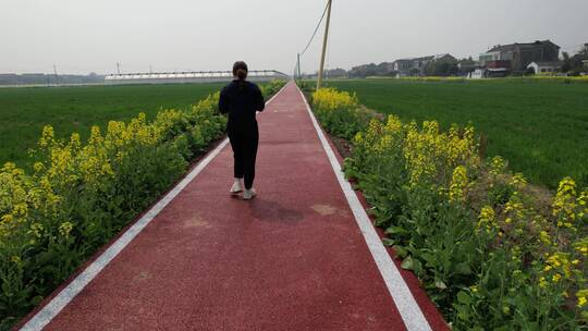 背影跟拍走在乡村小道春天油菜花新农村田园