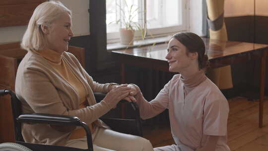 护士在疗养院与坐轮椅的老妇人交谈
