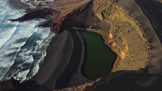 背景是绿水、黑沙和黄山的湖边有波浪的海滩