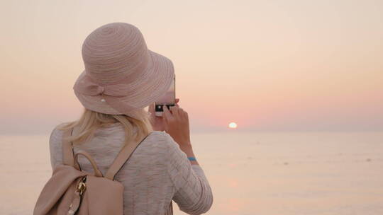 黄昏女人拍摄海边日落风景