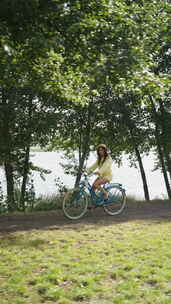 公园里河边或湖边骑自行车的垂直屏幕女人