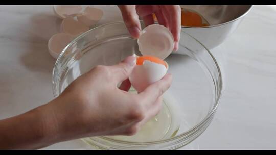 女性手打碎鸡蛋并将蛋黄从白色中分离出来